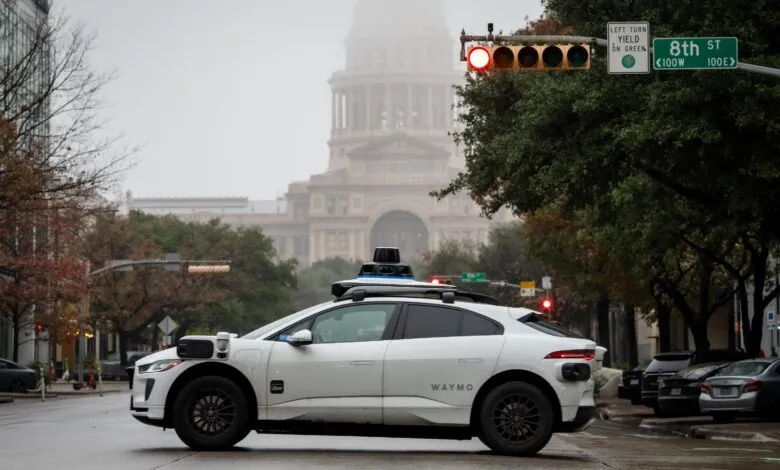 Waymo self-driving car at a red light with the Texas Capitol in the background.