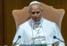 Archbishop Claudio Gugerotti seated, wearing white robes and zucchetto.