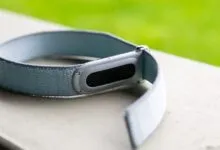 Close-up of a light blue Fitbit fitness tracker on a white surface.