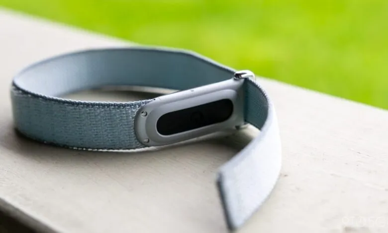 Close-up of a light blue Fitbit fitness tracker on a white surface.