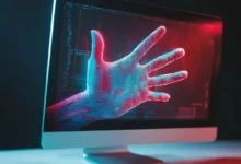 Computer monitor displays a digital hand with red and blue lighting effects.