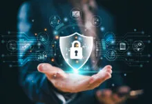 Hand holding a digital shield with a padlock, representing cybersecurity.