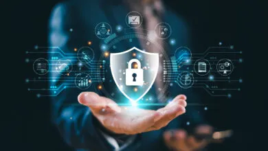 Hand holding a digital shield with a padlock, representing cybersecurity.