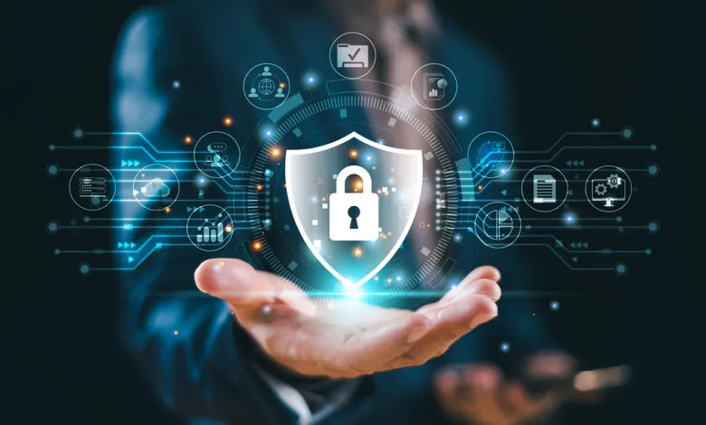 Hand holding a digital shield with a padlock, representing cybersecurity.