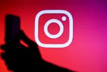 Instagram logo on screen with hand holding phone in foreground.