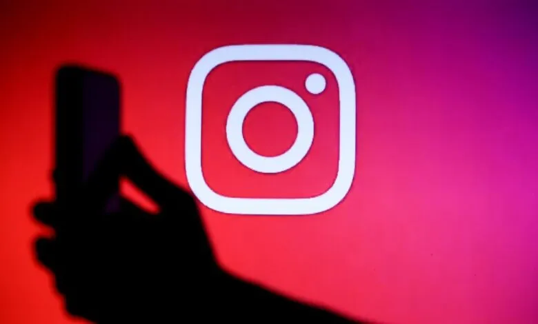 Instagram logo on screen with hand holding phone in foreground.