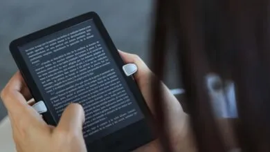 Hands holding a Kindle e-reader displaying text, focus on the screen.