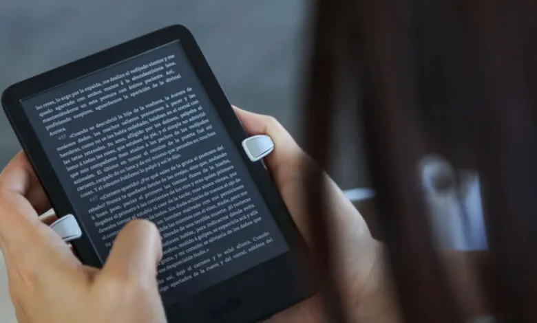 Hands holding a Kindle e-reader displaying text, focus on the screen.
