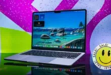 Silver laptop on reflective surface with a colorful background.