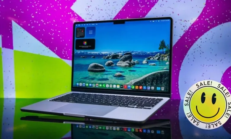 Silver laptop on reflective surface with a colorful background.