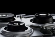 Close-up of three camera lenses on a silver device, black background.