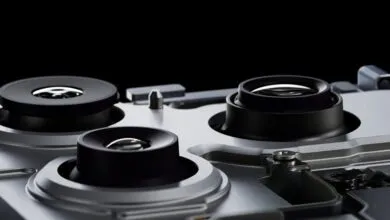 Close-up of three camera lenses on a silver device, black background.