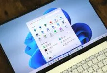 Asus Vivobook laptop displaying Windows 11 start menu on a wooden surface.