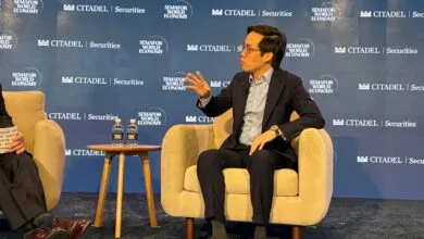 Man in suit gestures while seated at a Semafor World Economy event.