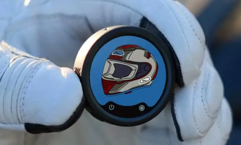 Gloved hand holds device displaying a helmet icon.