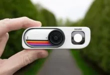 Hand holding a white Insta360 GO 3 camera with retro stripe design.