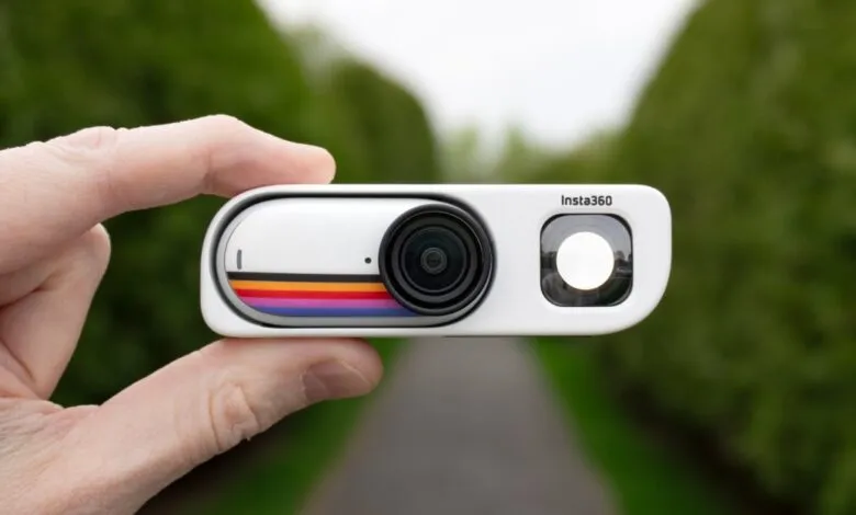 Hand holding a white Insta360 GO 3 camera with retro stripe design.