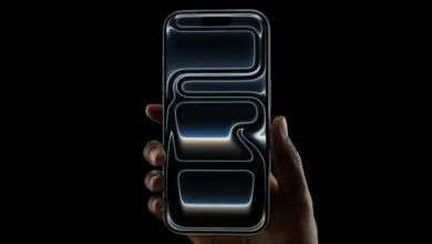 Hand holding a dark iPhone with a glowing abstract design on the screen.
