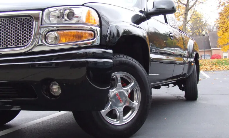 Close-up of a shiny black GMC Denali truck parked outdoors.