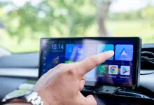 Hand touches Android Auto icon on car infotainment system.