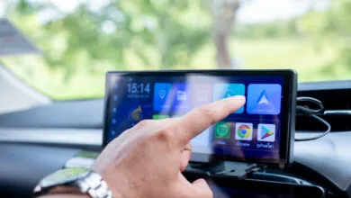 Hand touches Android Auto icon on car infotainment system.