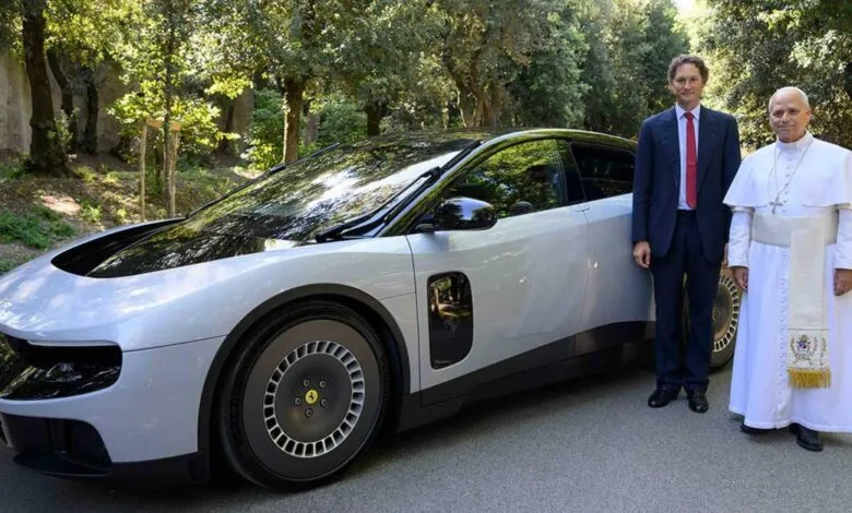 Pope Francis stands next to a man and a silver Ferrari Purosangue.