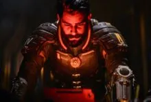 Close-up of a man in futuristic suit, illuminated by red light.