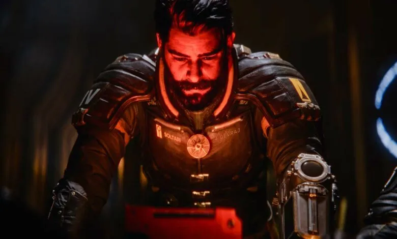 Close-up of a man in futuristic suit, illuminated by red light.