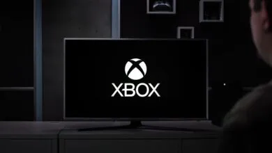 Xbox logo displayed on a large screen TV in a modern living room.