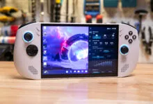 Lenovo Legion Go handheld gaming PC on a wooden surface, screen displaying performance settings.