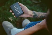 Person holding a Light Phone with menu options displayed on the screen.