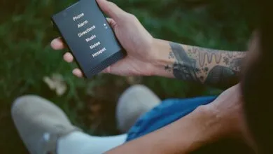 Person holding a Light Phone with menu options displayed on the screen.