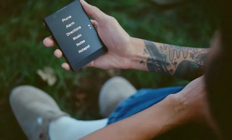 Person holding a Light Phone with menu options displayed on the screen.
