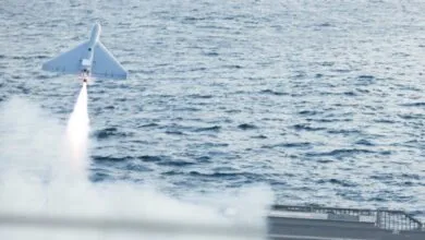 Attack drone launches from ship deck over ocean, smoke trail visible.
