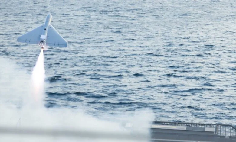 Attack drone launches from ship deck over ocean, smoke trail visible.