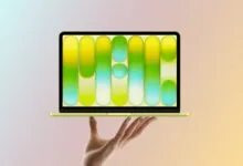 Hand holding a yellow laptop with a colorful abstract screen.