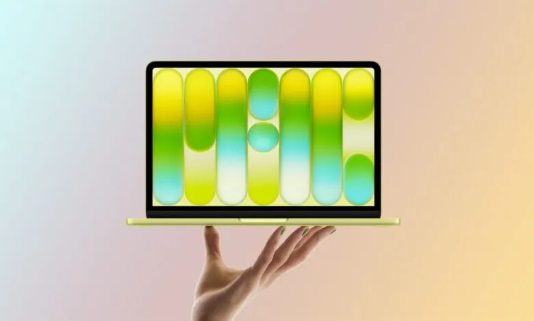 Hand holding a yellow laptop with a colorful abstract screen.