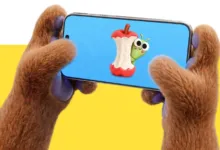 Furry hands hold phone displaying cartoon apple core with worm.