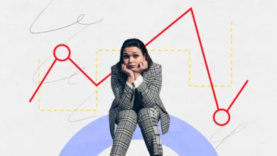 Worried woman in suit sits before a falling stock market graph.