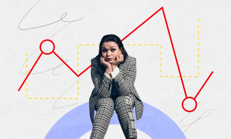 Worried woman in suit sits before a falling stock market graph.