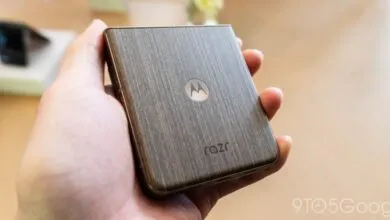 Hand holding a Motorola Razr phone with a wood-grain finish.