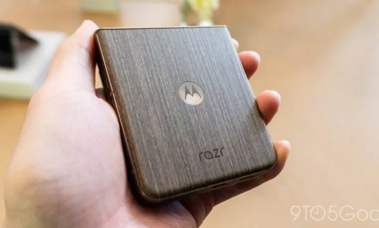 Hand holding a Motorola Razr phone with a wood-grain finish.