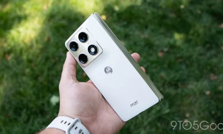 White Motorola Razr foldable phone held in hand, showcasing camera array.