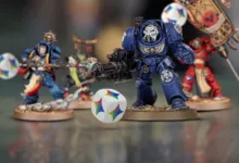Warhammer 40K miniatures with a colorful die in the foreground.