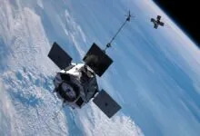 Two satellites orbit Earth, with clouds and blue sky visible below.