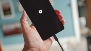 Hand holding a charging smartphone with a lightning bolt icon.