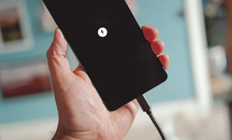 Hand holding a charging smartphone with a lightning bolt icon.