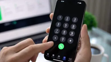 Person dialing a number on a smartphone with keypad displayed.