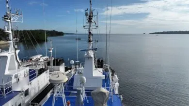 View from ship deck with white structures, antennas, and ocean backdrop.