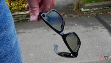 Hand holding Ray-Ban Meta smart glasses with black frames and tinted lenses.